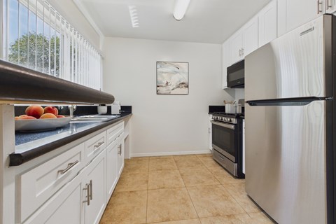 A kitchen with white cabinets and a stainless steel refrigerator.