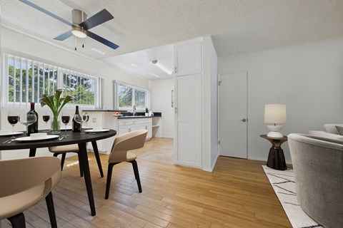 A modern dining room with a table set for two and a ceiling fan.