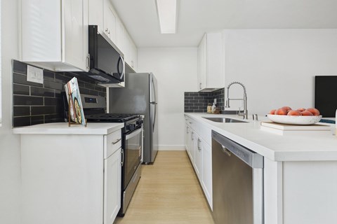 A modern kitchen with white cabinets and black appliances.
