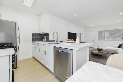 A modern kitchen with white cabinets and a marble countertop.