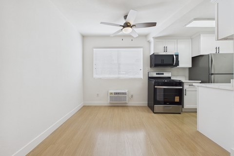 A kitchen with a fan and a fridge.