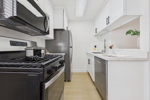 A modern kitchen with a black stove top oven and white cabinets.
