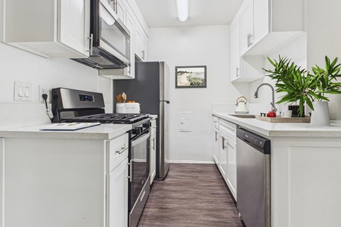 A modern kitchen with white cabinets and stainless steel appliances.