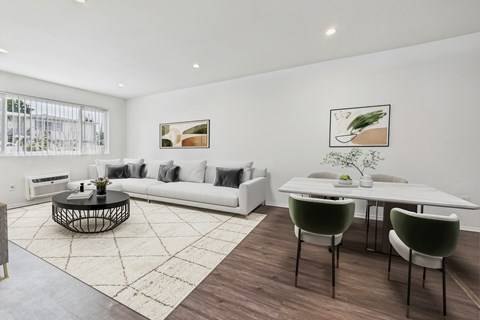 A modern living room with a white sofa, a coffee table, and two green chairs.
