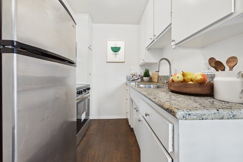 A kitchen with a stainless steel refrigerator and white cabinets.