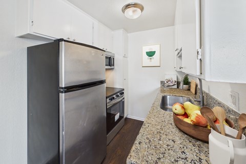 A kitchen with a granite countertop and a black refrigerator.