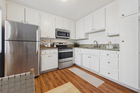 A kitchen with white cabinets and a stainless steel refrigerator.