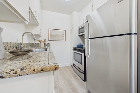 A kitchen with a granite countertop and stainless steel appliances.
