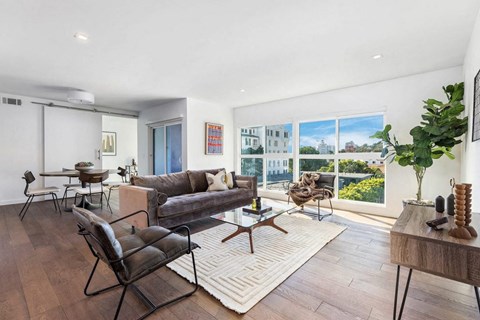 A living room with a couch, chairs, and a table with a vase on it.