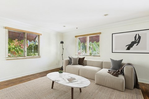 A living room with a grey couch, a white coffee table, and a painting on the wall.