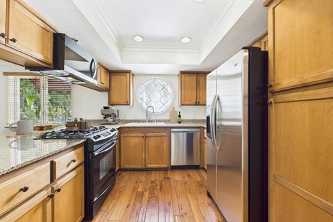 A kitchen with wooden cabinets and a stainless steel refrigerator.