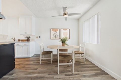 A dining room with a table set for two and a ceiling fan.