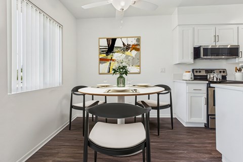 A dining room with a table set for two and a painting on the wall.