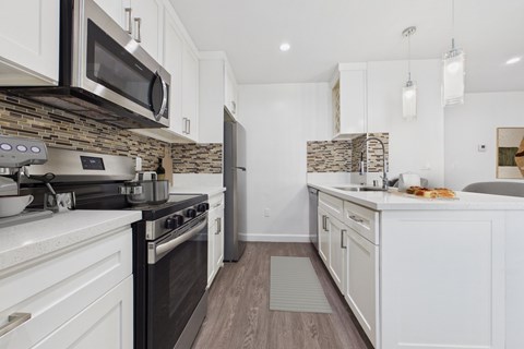 A kitchen with a black stove top oven and white cabinets.