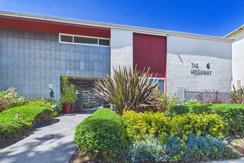 The Hideaway building with a red door and a sign on the wall.