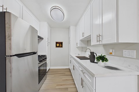 A kitchen with white cabinets and a black refrigerator.
