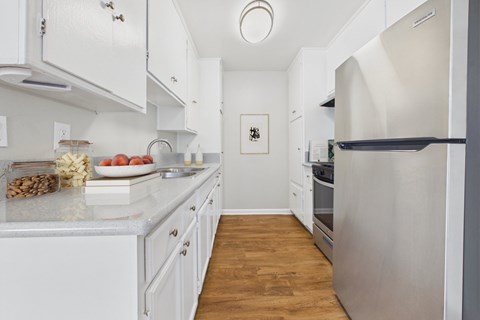 A kitchen with white cabinets and a fridge.