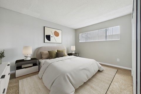 A bedroom with a large bed and a nightstand with a lamp.