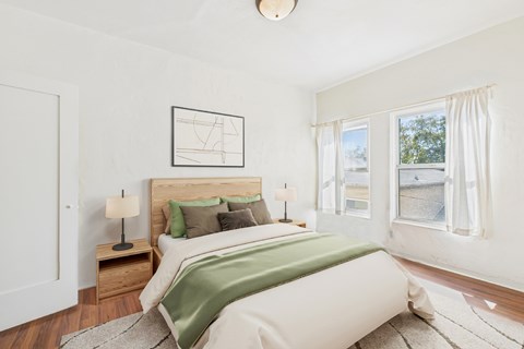 A bedroom with a large bed and a window with curtains.