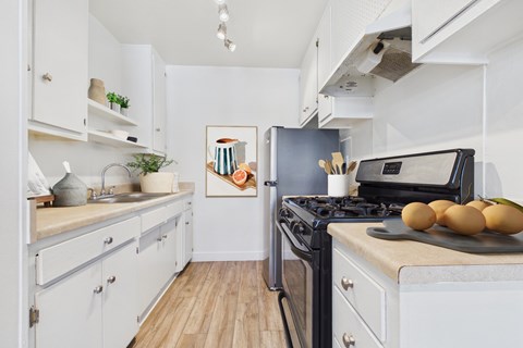A kitchen with a black stove top oven and a black fridge.