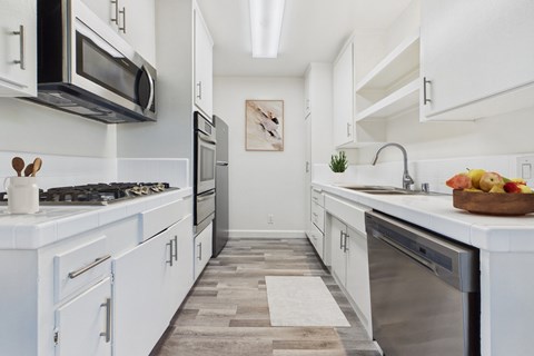 A modern kitchen with white cabinets and a wooden floor.