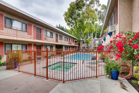 A pool surrounded by a red fence and a building with red trim.