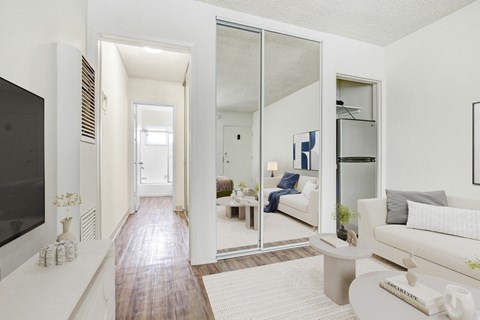 A modern living room with a white couch and a television on the left side.
