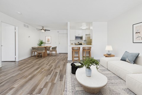 A living room with a white couch, a coffee table, and a dining table with chairs.