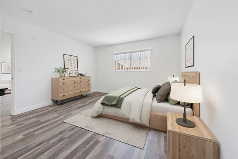A bedroom with a bed, nightstand, and a dresser with a plant on top.