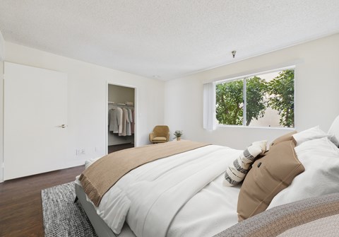 A bedroom with a large bed and a window overlooking trees.