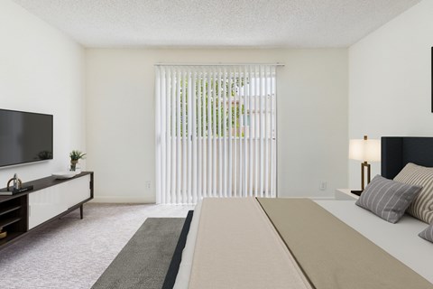 A bedroom with a large bed and a television on the wall.
