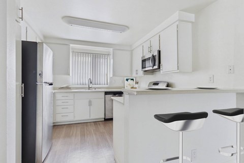 A kitchen with white cabinets and a black fridge.