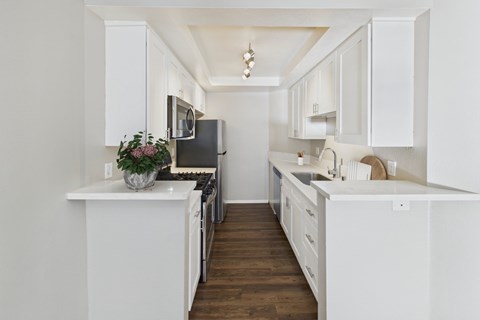 A kitchen with white cabinets and a black fridge.