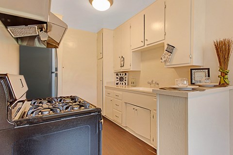 A black stove sits in a kitchen with white cabinets.