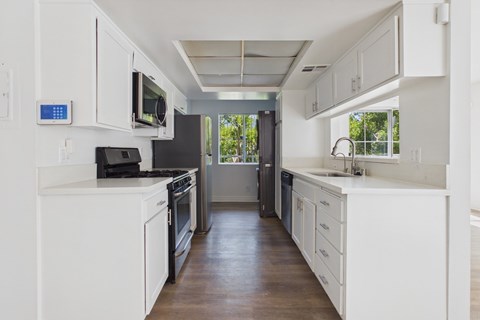 A modern kitchen with white cabinets and appliances.
