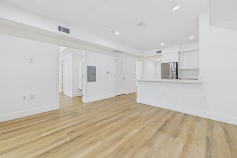 A spacious room with wooden flooring and white walls.