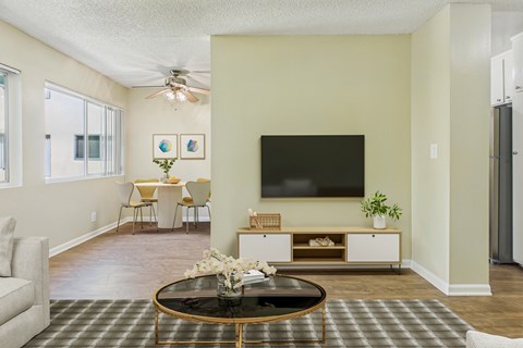 A living room with a black coffee table and a flat screen TV mounted on the wall.