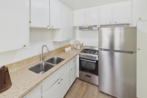 A kitchen with white cabinets and a stainless steel refrigerator.