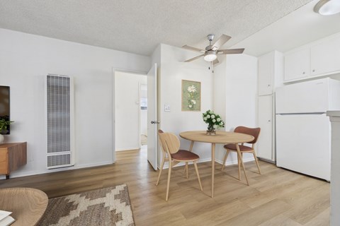 A dining room with a table set for two and a ceiling fan.