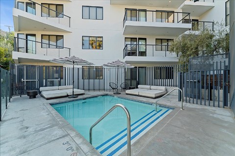 A swimming pool in front of a white building with black railings.