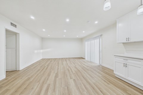 A spacious room with wooden flooring and white walls.