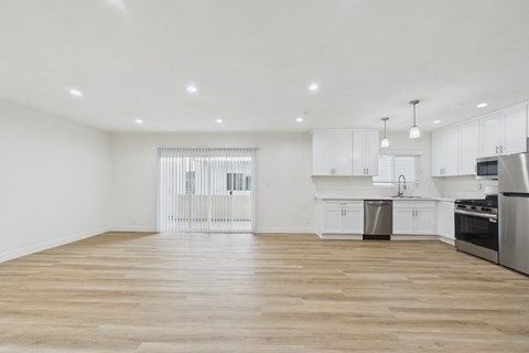 A kitchen with white cabinets and a wooden floor.