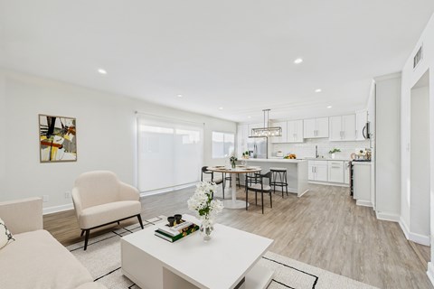 A modern kitchen and living room with a dining table and chairs.