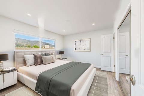 A bedroom with a large bed and a view of the mountains outside the window.