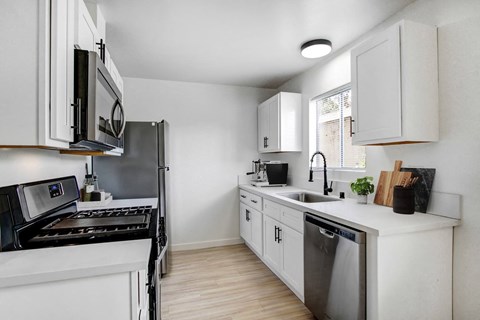 A modern kitchen with white cabinets and black appliances.