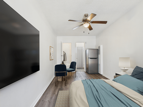 A bedroom with a bed, chair, and a ceiling fan.