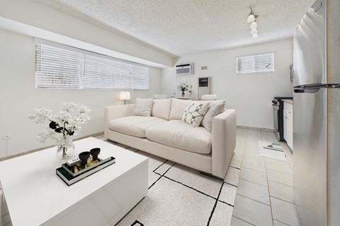 A white couch with a vase of flowers on a coffee table in a modern living room.