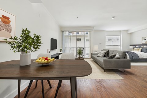 A dining table with a bowl of fruit and a vase of flowers on it.