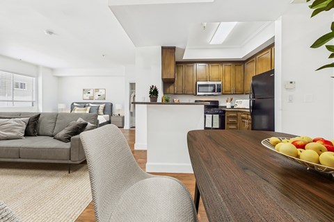 A modern kitchen with a wooden island and a dining table with a bowl of fruit on it.
