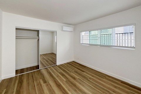 A room with wooden floors and a window with blinds.